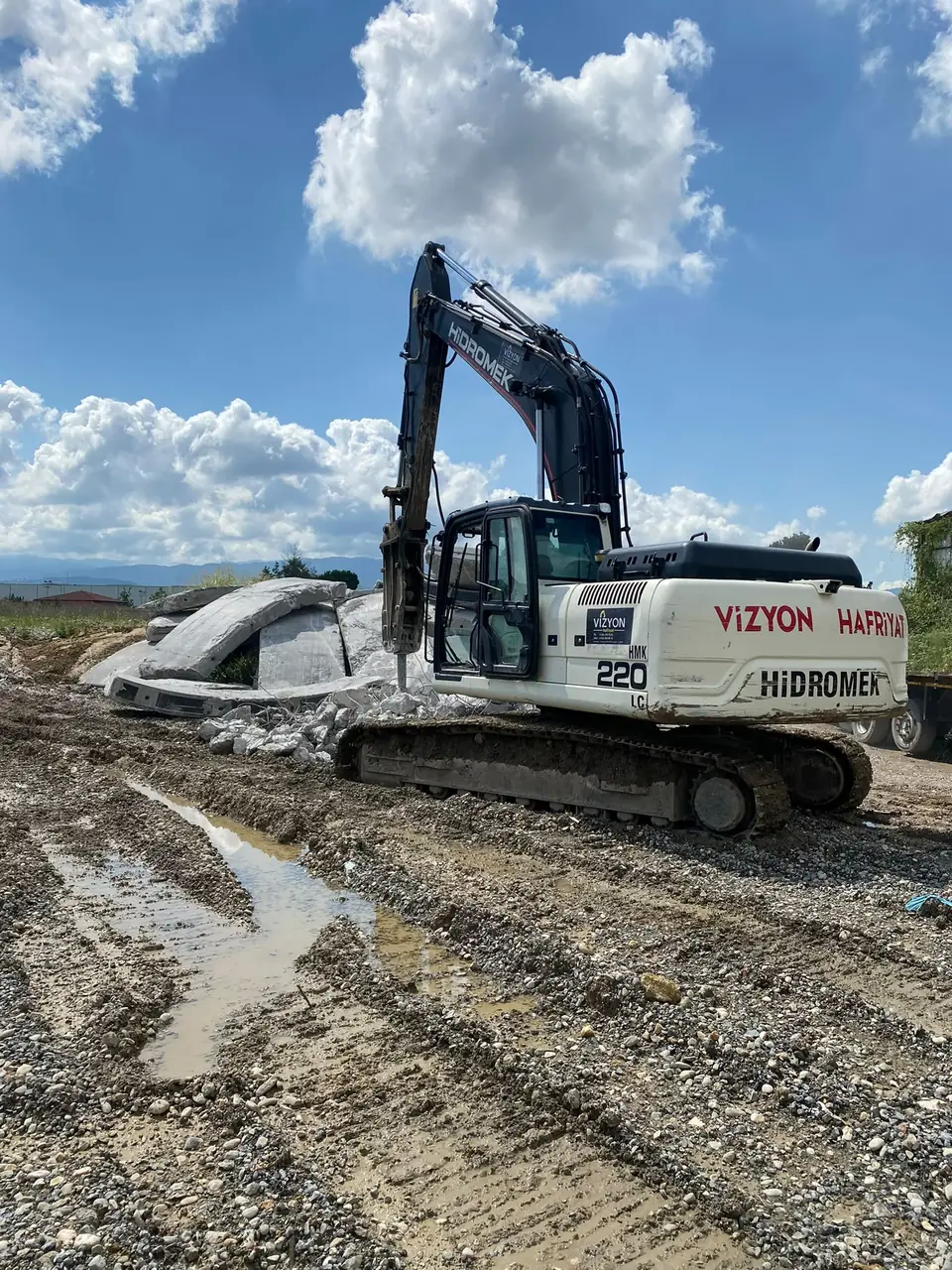 Vizyon Hafriyat logolu Hidromek 220 ekskavatör çamurlu sahada