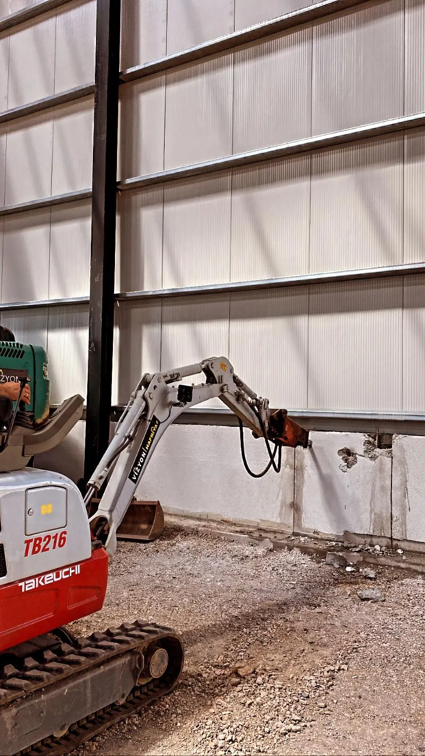 Mini ekskavatör fabrika içinde kırıcı ile çalışıyor